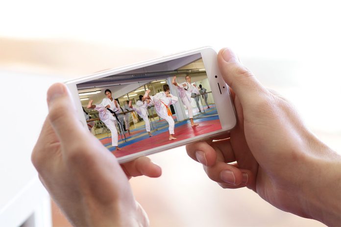 Hands holding phone with martial arts class video.