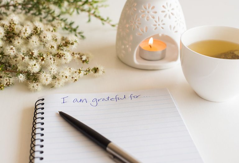 Grateful written on notebook with a candle.